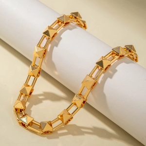 Detail of gold punk style choker with U-shaped links and pyramid rivets on white roll