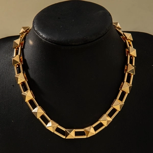 Close-up of a punk-style gold choker necklace with 3D pyramid rivets on a neck mannequin