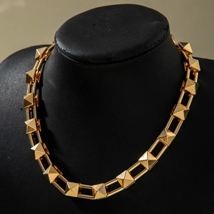 Close-up of golden punk style pyramid stud necklace with polished chunky metal chain links