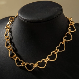 Detailed view of interconnected gold hollow heart-shaped links on a black necklace display