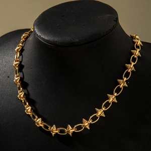 Detail of chunky gold chain necklace featuring punk style metal spikes and polished finish