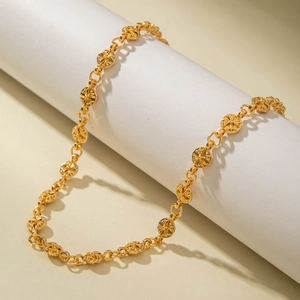 Detailed close-up of gold punk hip hop chain with engraved floral round links on white prop