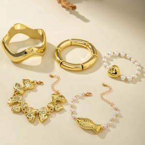 Ensemble de cinq bracelets dorés vintage avec nœuds et perles sur un fond chaleureux