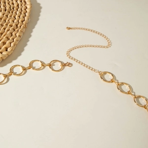 Close-up of golden metal waist chain featuring large round rings and adjustable lobster clasp