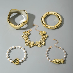 Ensemble de cinq bracelets dorés avec nœud, perles et joncs en métal texturé