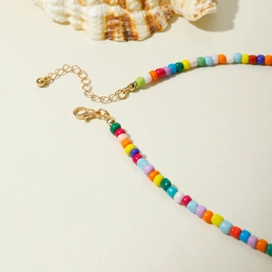 Collier de perles bohème colorées avec fermoir doré sur fond de coquillages marins