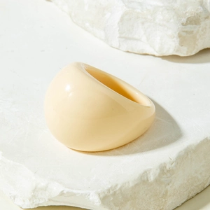 Macro view of a creamy beige chunky acrylic ring on a natural stone surface