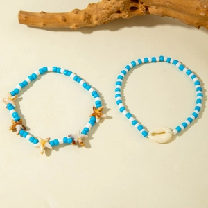 Detail of blue and white beaded anklets with starfish and seashell charms on wood