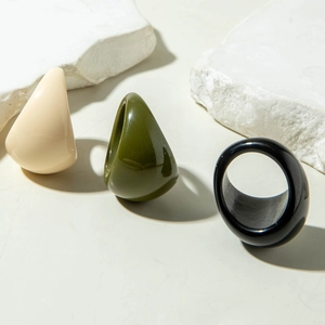 Detailed view of minimalist oval acrylic rings in beige, olive green, and classic black