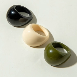 Close-up of set of three chunky acrylic resin rings in black, cream, and dark green