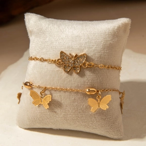 Gold butterfly anklet set with sparkling rhinestones on a white jewelry pillow