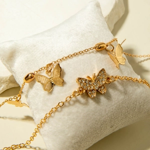 Detailed close-up of gold butterfly anklet set with sparkling rhinestones on white velvet