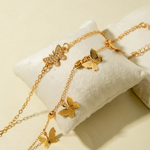 Detailed close-up of golden butterfly anklets with zircon inlay and brushed texture