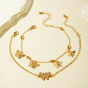 Detail of layered gold butterfly anklets with crystal inlay on a minimalist stone setting