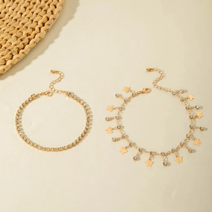Close-up of gold layered anklets with diamond eye pendants and butterfly charms