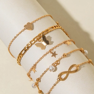 Detail of five-piece gold butterfly and pearl anklet set with heart and star charms