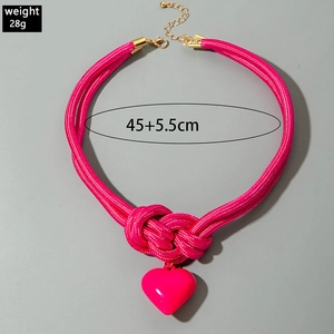 Détail du collier en corde tressée magenta avec nœud décoratif et pendentif cœur rose
