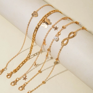 Close-up of a 5-piece gold anklet set with butterfly, heart, and star charms on a white stand
