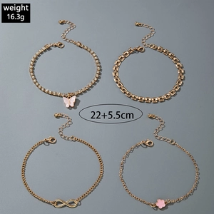 Detail of four-piece gold layered anklet set with butterfly, flower, and infinity charms