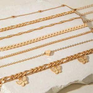 Detail of 7pcs gold butterfly and heart layered anklet set on textured stone