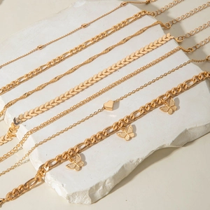 Detail of gold layered anklet set with butterfly pendants and heart charms on stone