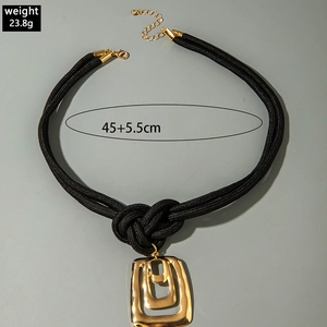 Détail de pendentifs carrés dorés à texture martelée sur un collier à cordon noir noué