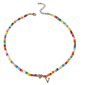 Collier bohème en perles colorées avec pendentif cœur doré et lettre V sur fond blanc