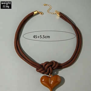 Détail du collier à nœud tressé marron foncé avec pendentif cœur brillant et fermoir doré