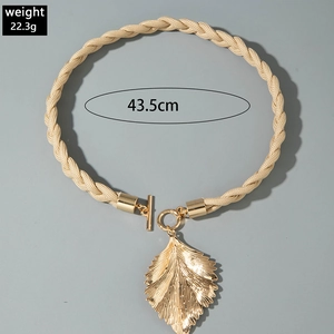 Détail du pendentif feuille dorée avec design noué sur un collier en cordon tressé