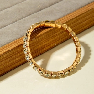 Makroaufnahme eines goldfarbenen Kristallarmbands auf einem grauen Samtschmuckständer