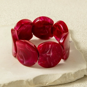 Macro detail of dark red marble textured acrylic beads on an elastic stretch bracelet