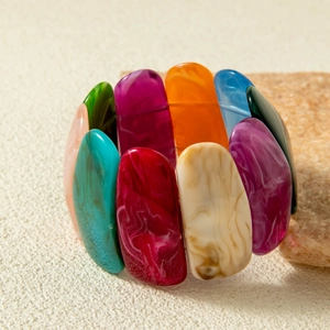 Detailed close-up of colorful marbled acrylic stretch bracelet on a textured stone base