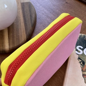 Close-up of contrast color storage bag with yellow canvas and red durable zipper