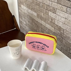 Close-up of pink and yellow bear canvas pouch with red zipper in a cozy cafe setting