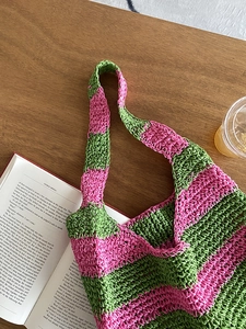 Detail showing pink and green checkered crochet texture of a large woven beach tote bag