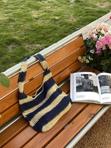Detail view of a handmade crochet tote bag with blue and white stripes on a wooden bench