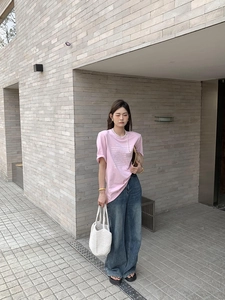 Modern casual look featuring a white woven handbag with a pink tee and wide-leg jeans