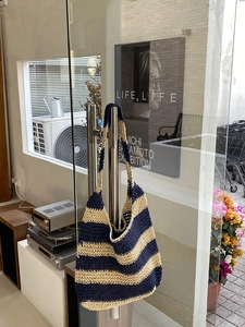 Detail of blue and beige striped straw tote bag with hand-woven hollow texture