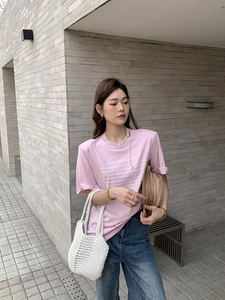 Detail of a white hand-woven straw tote bag paired with a casual summer outfit