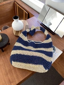 Close-up of handmade blue and beige striped straw tote bag on a wooden table setup