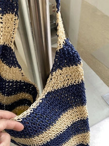 Detail of hand-woven striped straw tote bag showing navy and beige crochet texture