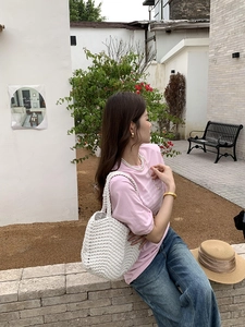 Outdoor lifestyle shot of a white hand-knitted tote bag paired with a casual summer outfit