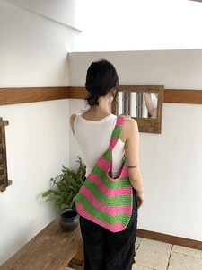 Close-up of pink and green striped crochet hobo bag with wide shoulder strap detail