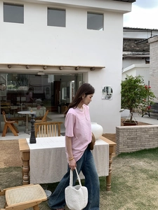Detail view of a white woven handbag paired with casual outfit in a bright outdoor setting