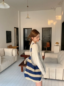 Detail shot of blue and white striped woven tote bag with chunky knit cardigan sweater