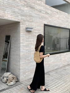 Detail of a beige handmade woven shoulder bag paired with a black knitted summer dress