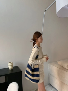 Detail of a large blue and beige striped woven straw tote bag paired with a knit dress