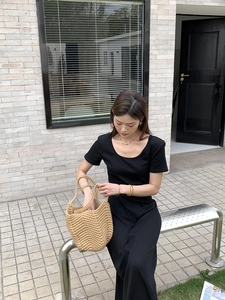 Detail view of khaki woven straw bucket bag paired with black short sleeve dress