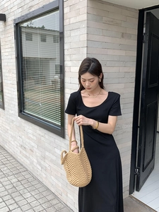 Close-up of hand-woven beige shoulder bag texture with black dress in outdoor light