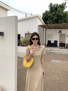 Detail of elegant khaki knitted midi dress paired with yellow handmade woven beach bag